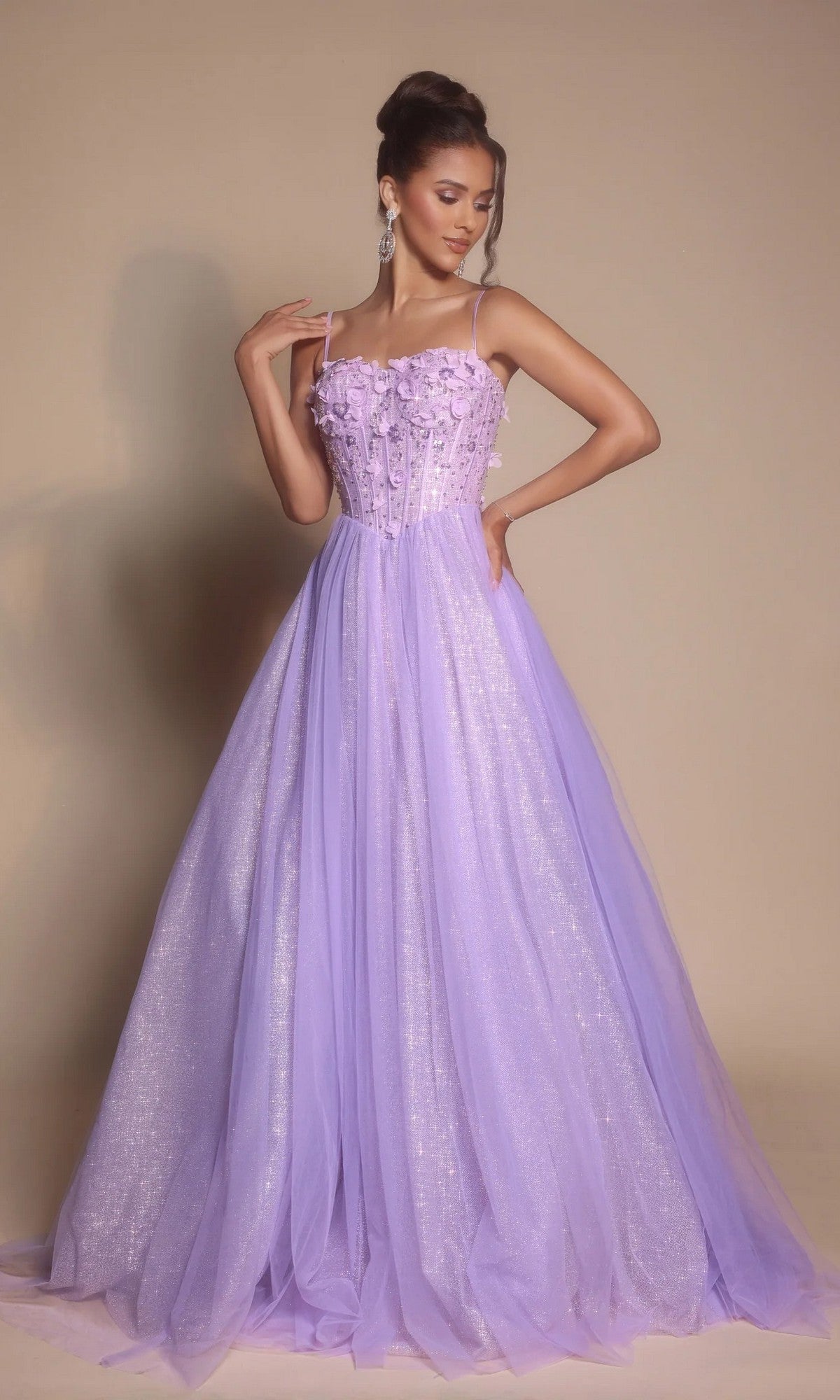 Woman in a lilac Glitter Prom Ball Gown (Portia and Scarlett PS26146) featuring floral details, boned-corset bodice, sheer straps, and a full tulle skirt stands against a neutral background.